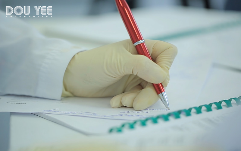 A scientist writing on paper in a lab.